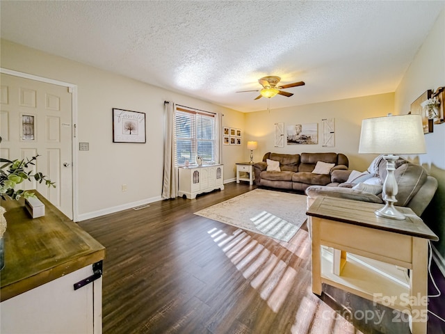living area with baseboards, ceiling fan, dark wood-style flooring, and a textured ceiling