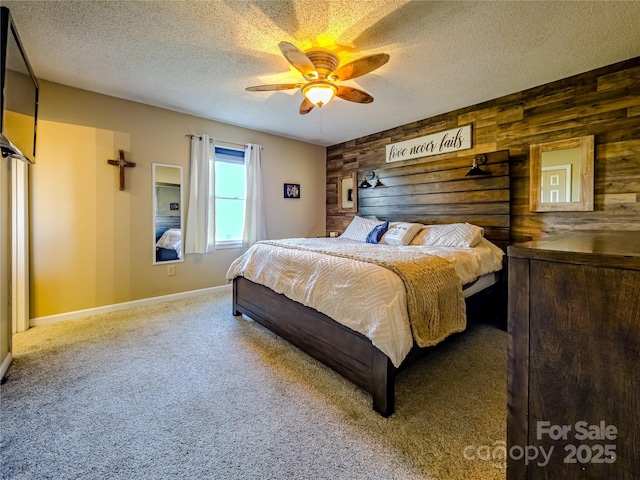 carpeted bedroom featuring wooden walls, baseboards, and a textured ceiling