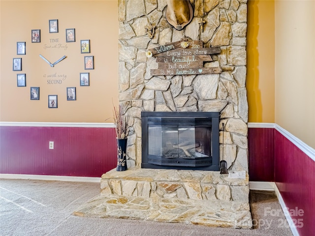 interior details with a stone fireplace, carpet flooring, wainscoting, and baseboards