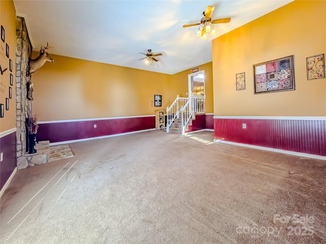 carpeted living room featuring a wainscoted wall and a ceiling fan