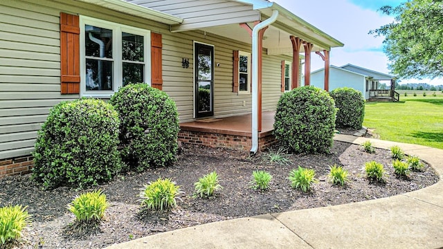view of exterior entry with covered porch and a yard