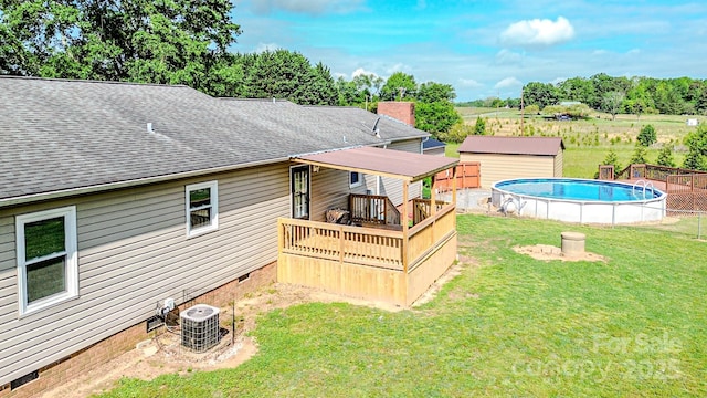 back of property featuring crawl space, a lawn, a deck, an outdoor pool, and central AC