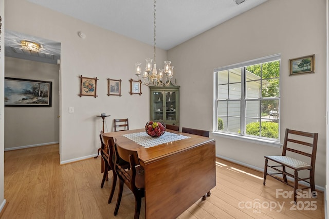 dining space with light wood-style flooring, a chandelier, and baseboards