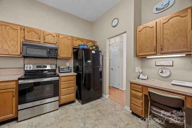 kitchen featuring black appliances, light countertops, vaulted ceiling, and baseboards