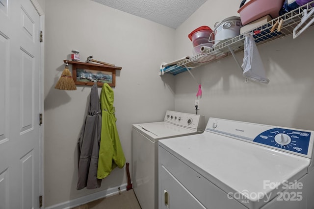 laundry area with independent washer and dryer, a textured ceiling, and baseboards