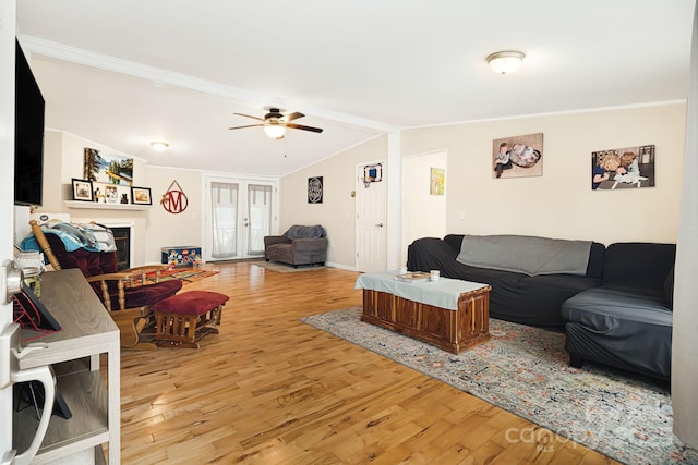 living area with vaulted ceiling, ornamental molding, a fireplace, and wood finished floors