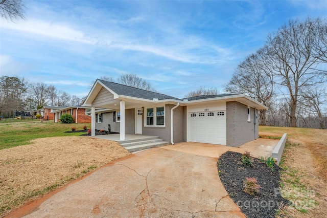 single story home featuring brick siding, a front yard, covered porch, driveway, and an attached garage