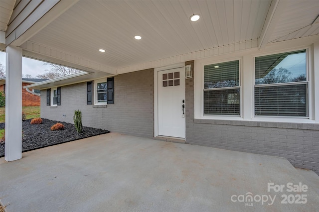 entrance to property with brick siding and a patio area