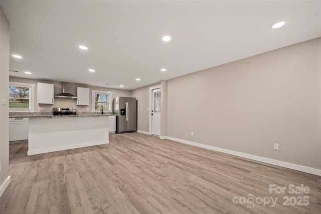 kitchen with light wood-style flooring, white cabinetry, recessed lighting, stainless steel appliances, and wall chimney range hood