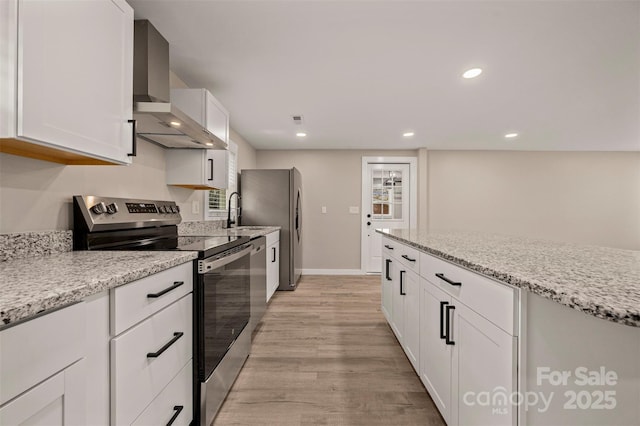 kitchen with light wood-type flooring, white cabinetry, recessed lighting, stainless steel appliances, and wall chimney range hood