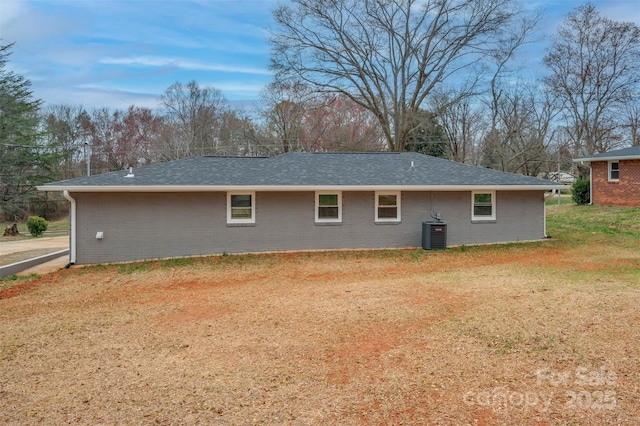 back of house featuring a lawn, brick siding, central AC, and a shingled roof