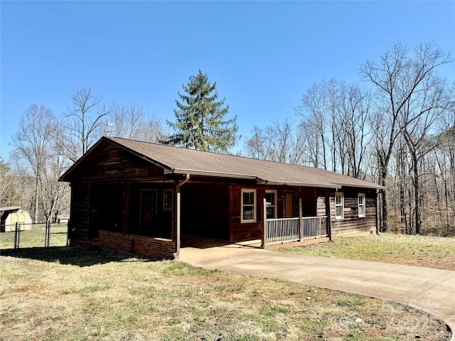 view of front of house featuring a porch, concrete driveway, fence, and a front yard