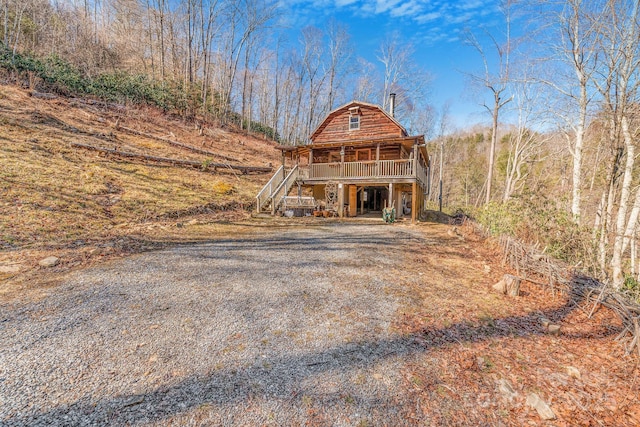 view of front of property with a gambrel roof, gravel driveway, and stairs