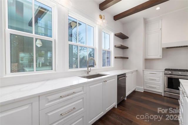 kitchen featuring stainless steel gas range oven, dark wood finished floors, light stone counters, white cabinets, and a sink