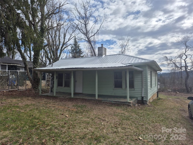 back of house featuring fence, metal roof, a chimney, a yard, and a patio area