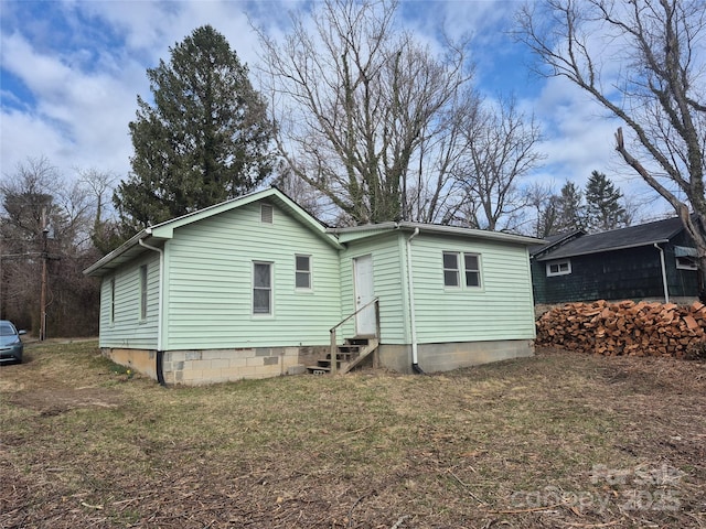 rear view of house featuring entry steps and a lawn