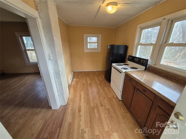 kitchen with a wealth of natural light, electric range, baseboard heating, and light wood-style flooring