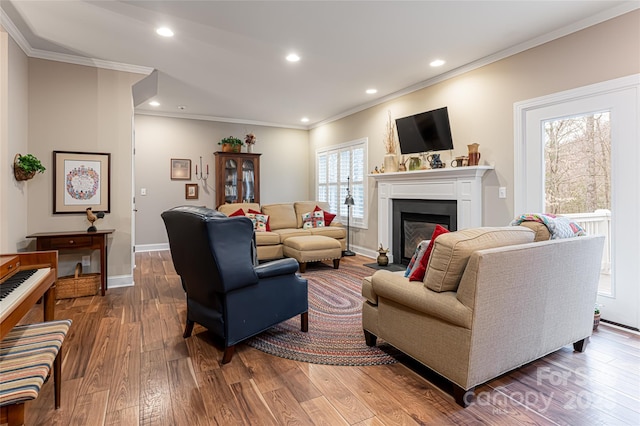 living room with a glass covered fireplace, crown molding, recessed lighting, and dark wood-style floors