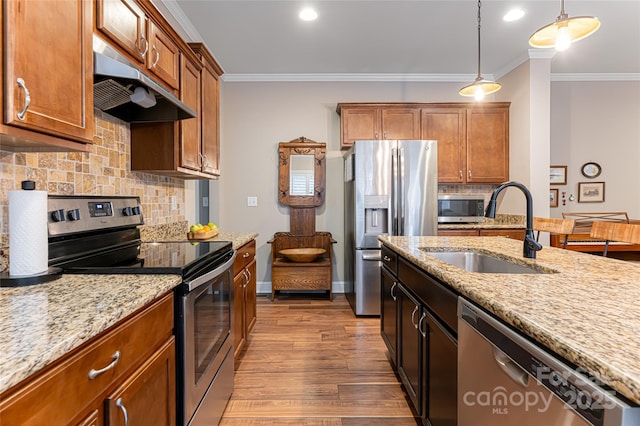 kitchen featuring a sink, under cabinet range hood, ornamental molding, stainless steel appliances, and dark wood-style flooring