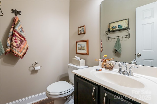 bathroom featuring toilet, vanity, and baseboards