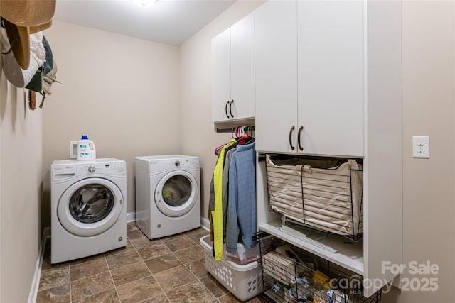 clothes washing area with washer and dryer, stone finish floor, cabinet space, and baseboards