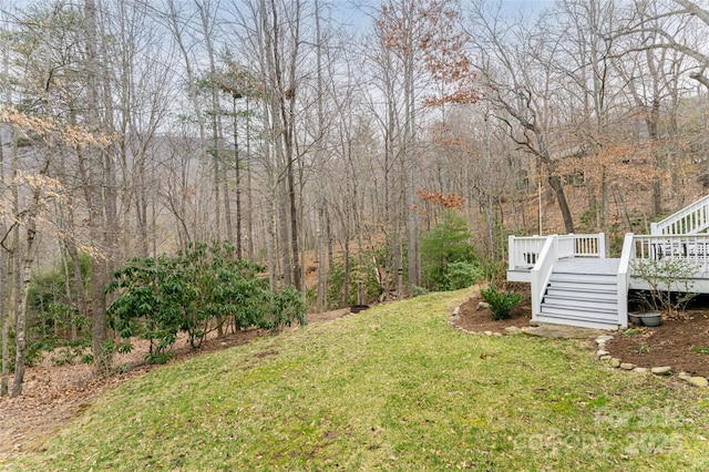 view of yard with a wooden deck, stairs, and a view of trees