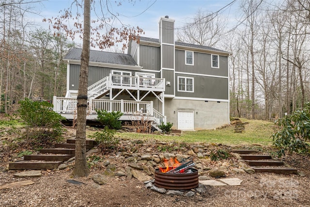 back of property featuring stairs, a wooden deck, roof with shingles, and a chimney