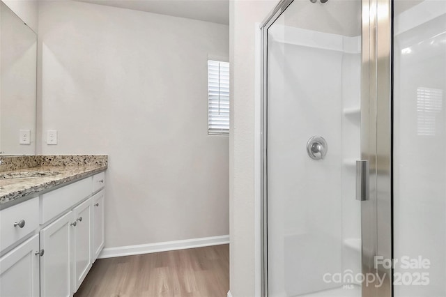 bathroom featuring baseboards, vanity, wood finished floors, and a shower stall