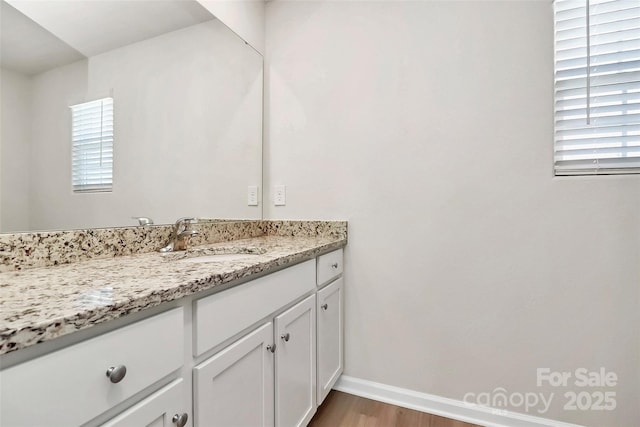 bathroom featuring baseboards, wood finished floors, and vanity