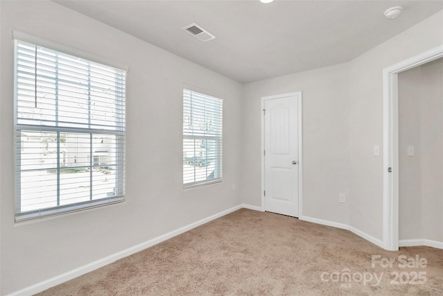 unfurnished room with carpet, visible vents, and baseboards