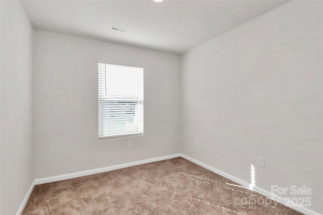 empty room featuring carpet flooring, visible vents, and baseboards