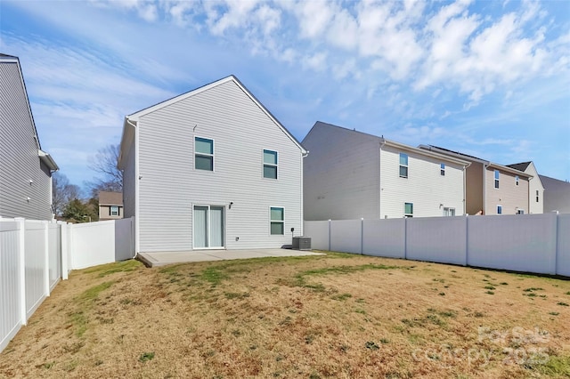 rear view of house with central air condition unit, a yard, a patio area, and a fenced backyard