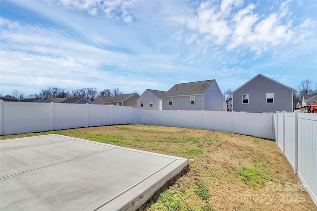 view of yard with a patio, a fenced backyard, and a residential view