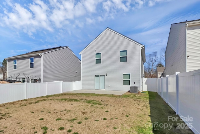 rear view of property featuring a lawn, central AC, a fenced backyard, and a patio area