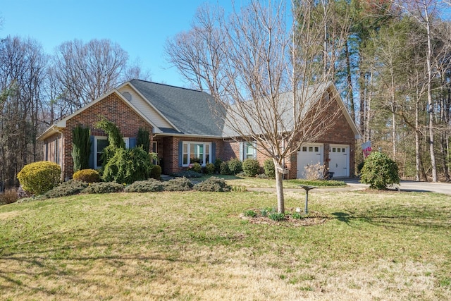 view of front facade featuring a front yard, an attached garage, brick siding, and driveway