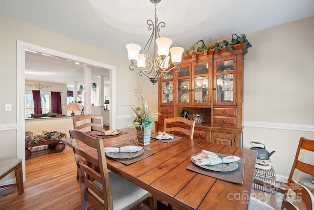 dining area with light wood-style floors and an inviting chandelier