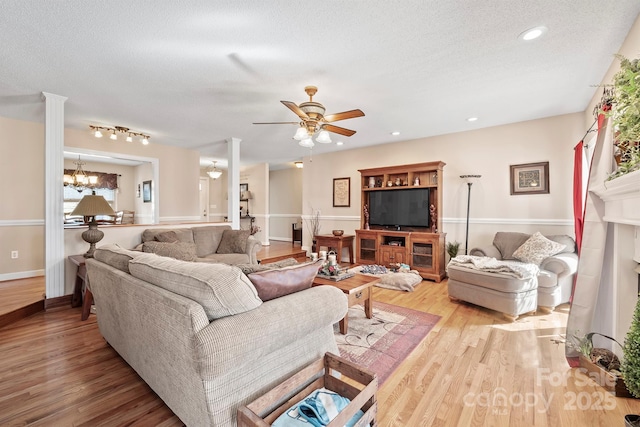 living area with ceiling fan with notable chandelier, a textured ceiling, wood finished floors, recessed lighting, and baseboards