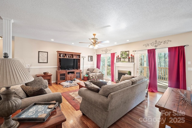 living room featuring a fireplace, plenty of natural light, light wood-style floors, and ceiling fan