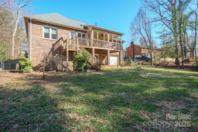 rear view of property with stairway, a ceiling fan, an attached garage, a lawn, and brick siding