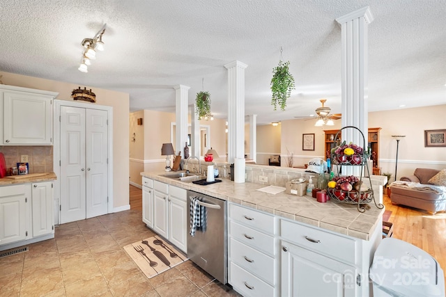 kitchen with ornate columns, a sink, open floor plan, dishwasher, and tasteful backsplash