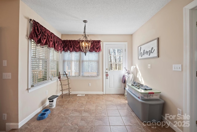 dining space with baseboards, a textured ceiling, and a chandelier