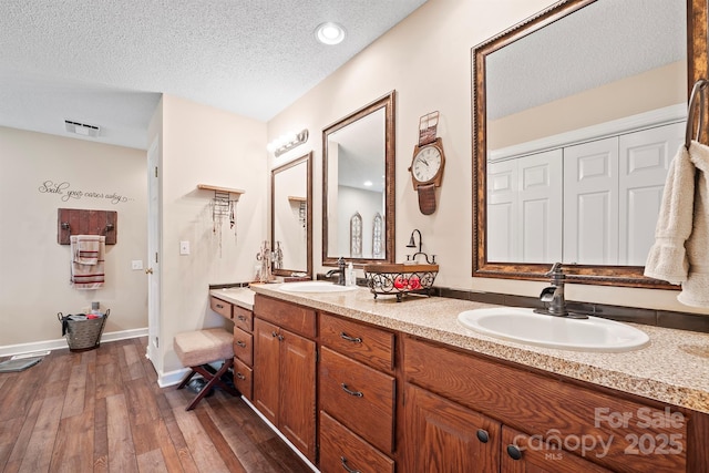 full bathroom featuring visible vents, a textured ceiling, hardwood / wood-style flooring, and a sink