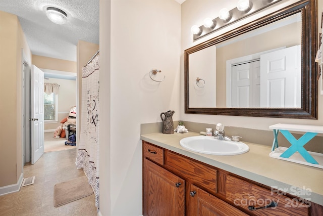 full bath with visible vents, a textured ceiling, vanity, and baseboards