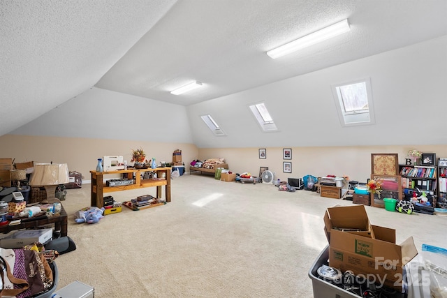 rec room with lofted ceiling with skylight, carpet flooring, and a textured ceiling