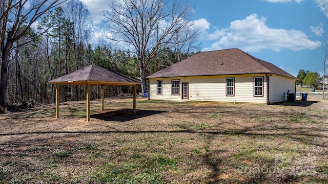 back of property with a carport and a lawn