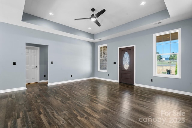 entryway with visible vents, baseboards, dark wood finished floors, a tray ceiling, and ceiling fan