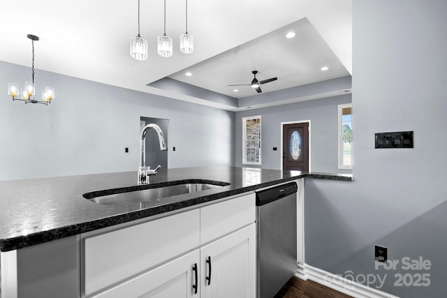 kitchen with white cabinetry, dark stone counters, a sink, dishwasher, and a raised ceiling