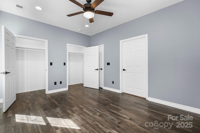 unfurnished bedroom featuring recessed lighting, baseboards, multiple closets, and wood finished floors