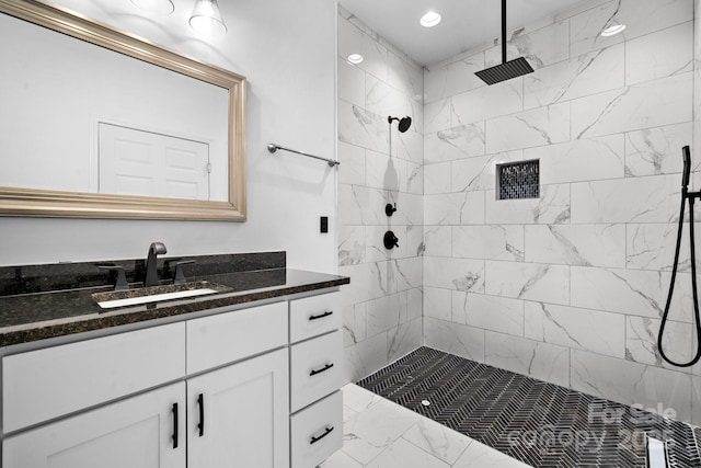 bathroom with recessed lighting, vanity, and a tile shower