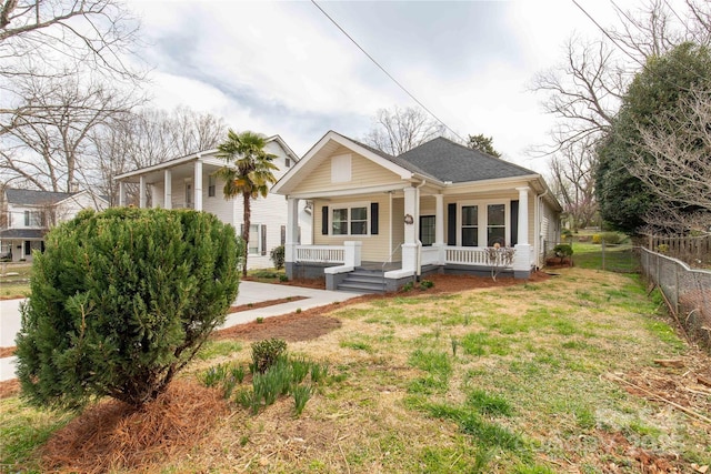 bungalow-style house featuring a porch, a front yard, and fence